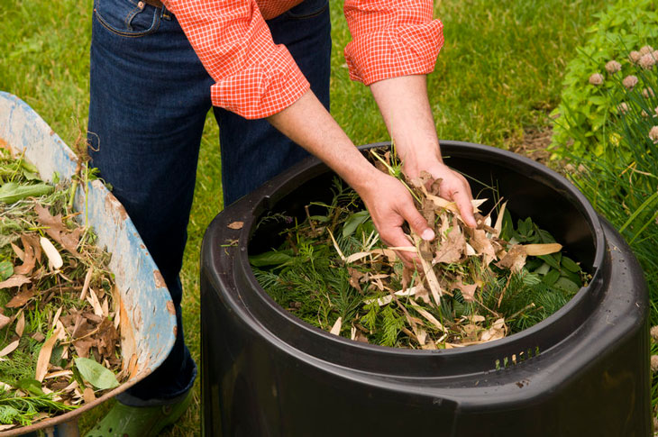 Someone adds leaves to a backyard composter. Photo by Metro: oregonmetro.gov