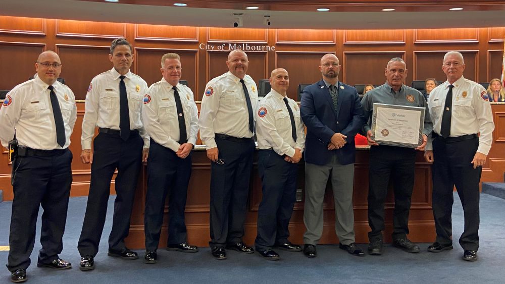 Standing in the council chamber are members of the Melbourne Fire Department with the mayor and Michael Morash who is holding the ISO Class 1 recognition plaque.