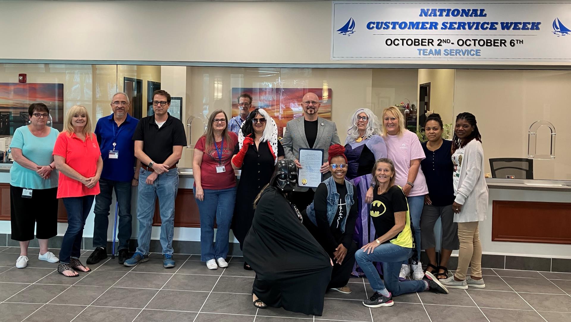 Mayor Alfrey and Utility Billing and Collections employees in front of National Customer Service Week banner.