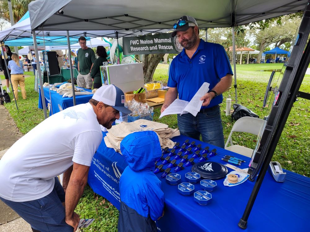 A man and a young child talk to a City representative at the ECO booth at Indian River Lagoon Day, Front Street Park.