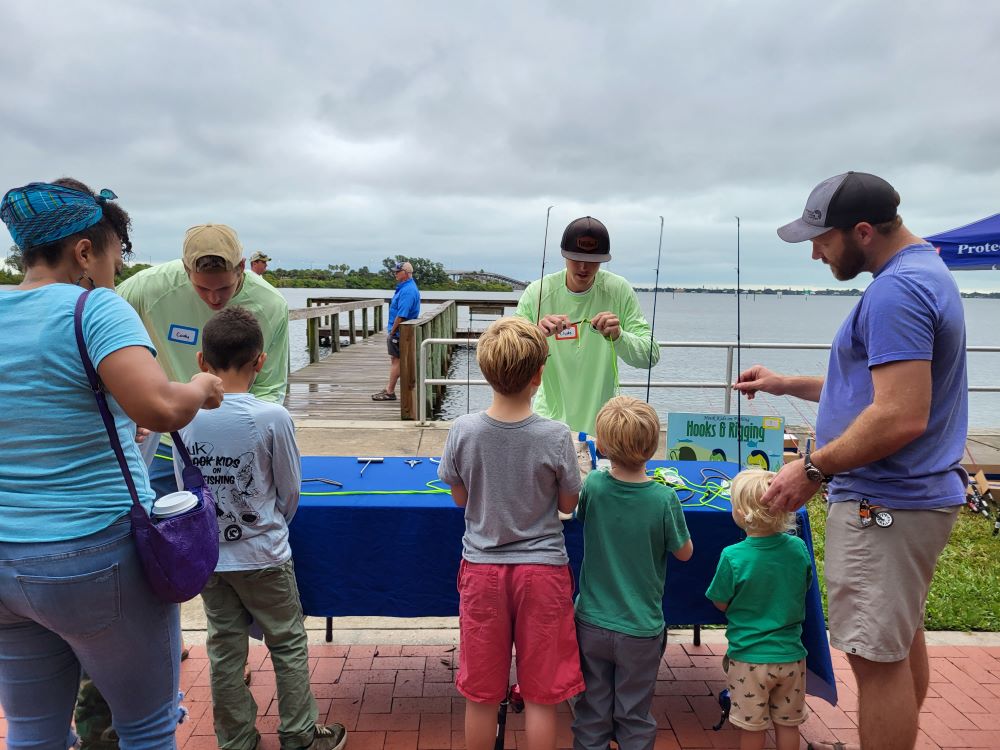 A man shows a group of kids with adults a fishing line at Indian River Lagoon Day, Front Street Park.