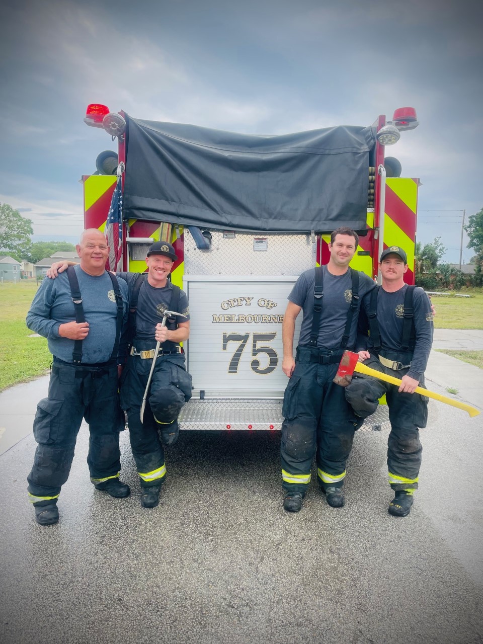 Four Melbourne firefighters standing in front of fire engine 75.