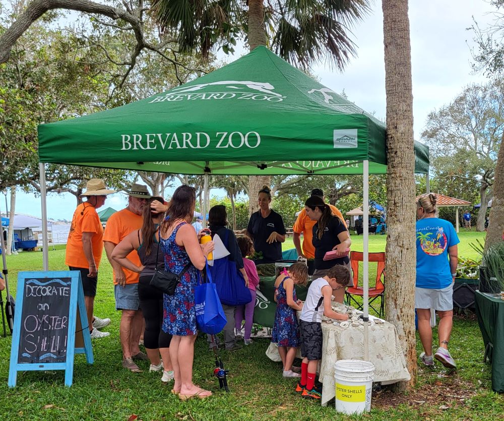 Attendees visit the Brevard Zoo tent and 2 kids decorating oyster shells