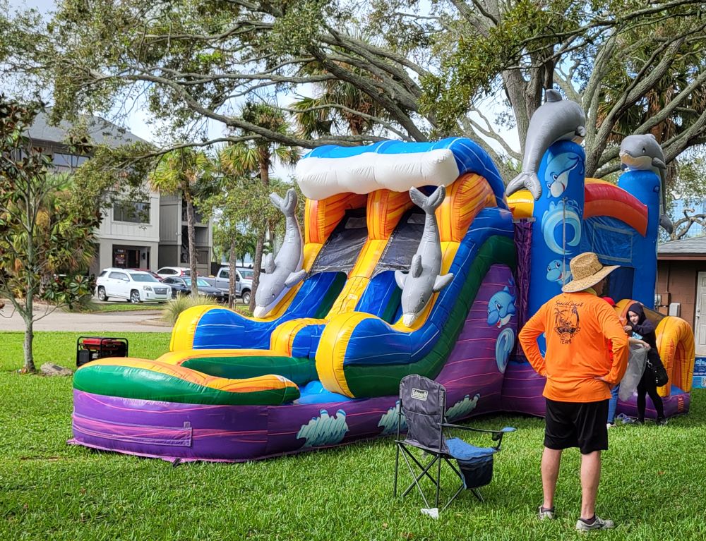 Volunteer in front of large inflatable slide and child at the slide entrance