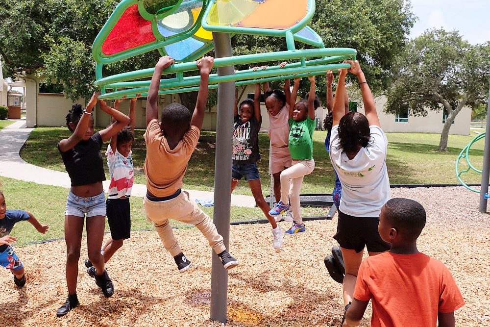 10 kids playing on and around playground spinner