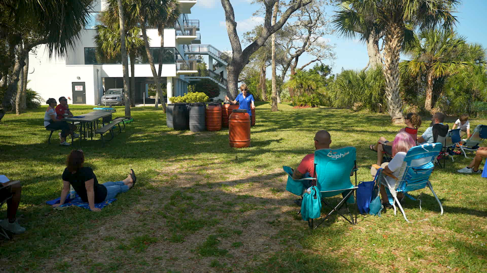 Presenter with rain barrel while workshop attendees watch on the lawn of Green Gables