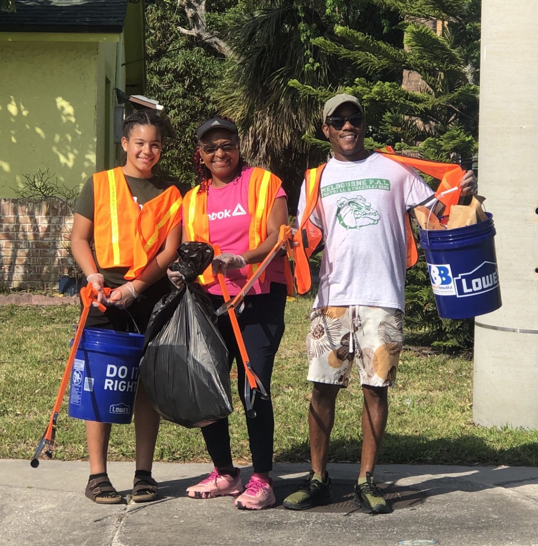 Three Trash Bash volunteers with buckets and a garbage bag filled with trash